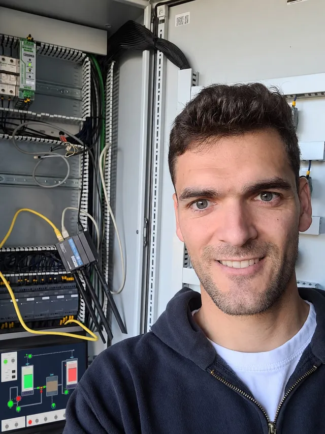Bart van ASK Engineering bij de geopende schakelkast, met de Teltonika-router, de PLC-modules en het HMI-scherm van de waterzuivering.