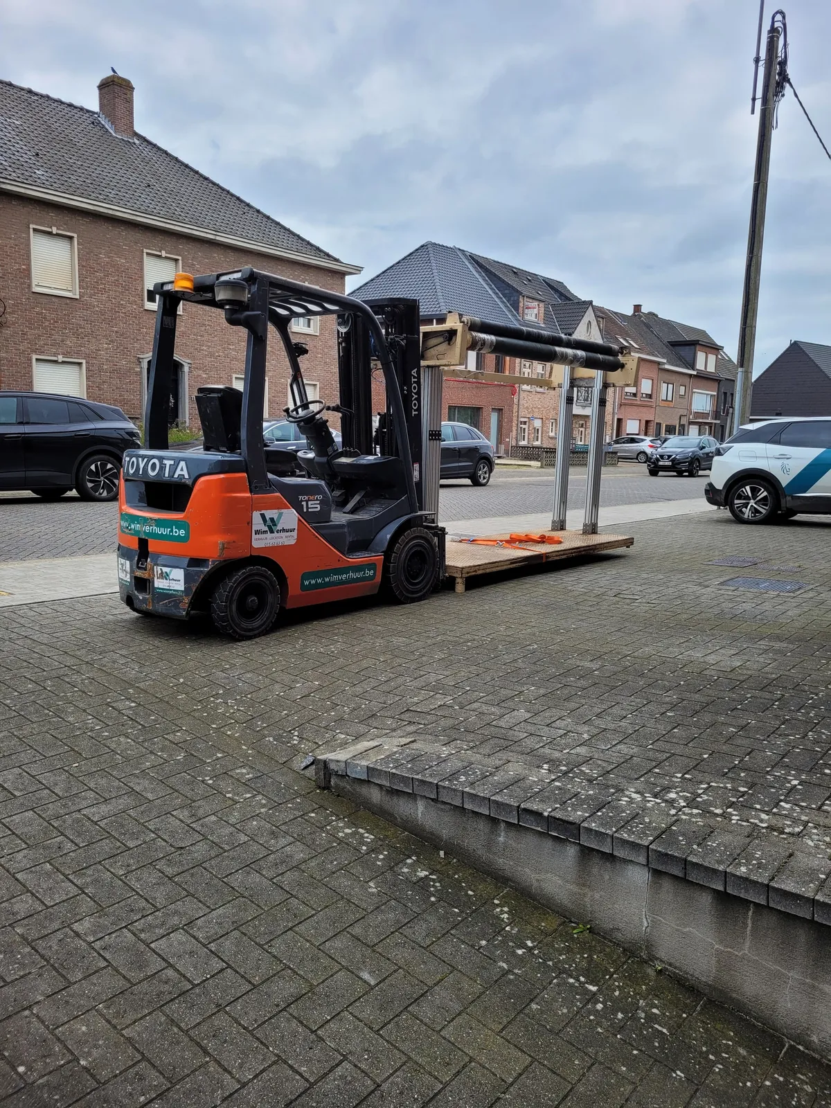 Een heftruck brengt de grote rollen stof aan.